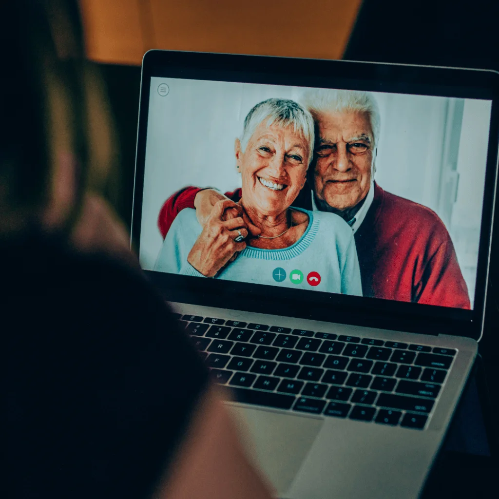 Persona en videollamada con una pareja mayor en un portatil, asesorando sobre ampliaciones y reducciones de capital online.