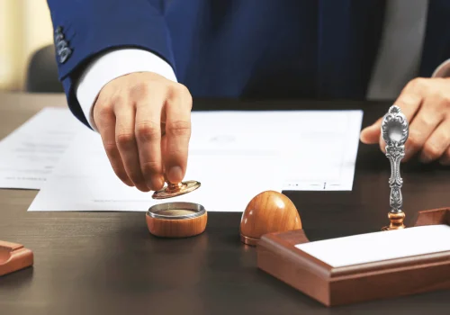 A lawyer stamps a document at their desk, certifying its authenticity