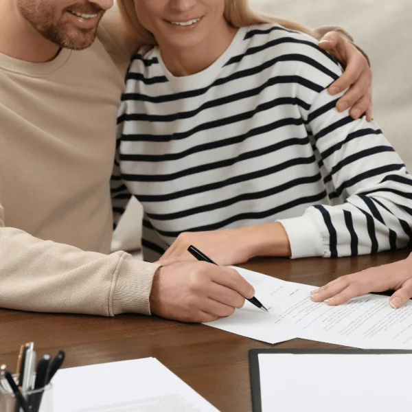 Couple smiling while signing legal documents, completing the online web publication certification process.