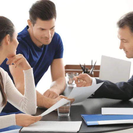 Legal advisor explaining documents to a young couple in a meeting, ensuring online web publication certification.