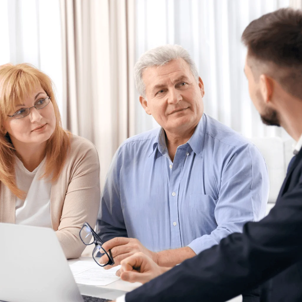 Pareja mayor en reunion con un asesor financiero, discutiendo opciones para ampliaciones y reducciones de capital online.