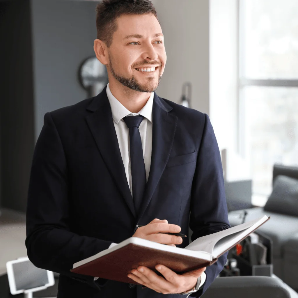 Empresario en traje negro con libro en mano, sonriendo mientras organiza el proceso de disolución y liquidación online.