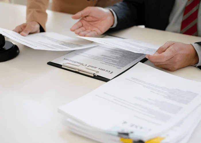 Dos profesionales revisando y firmando documentos legales en una oficina, gestionando la legalización de libros online.