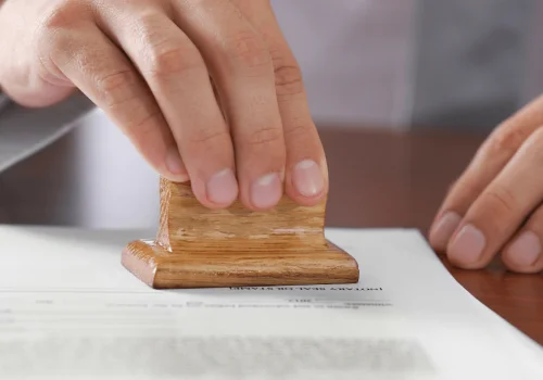Hand applying a stamp on a legal document, ensuring the validity of procedures
