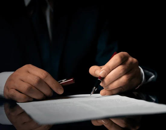 A lawyer in a suit signs a legal document with an elegant pen, a fundamental process in online revocation of powers