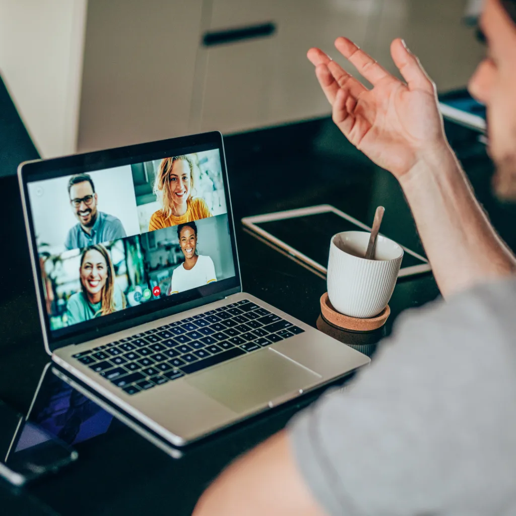 Hombre en videollamada con varias personas en una laptop, participando en una consulta legal sobre el otorgamiento y revocación de poderes online.